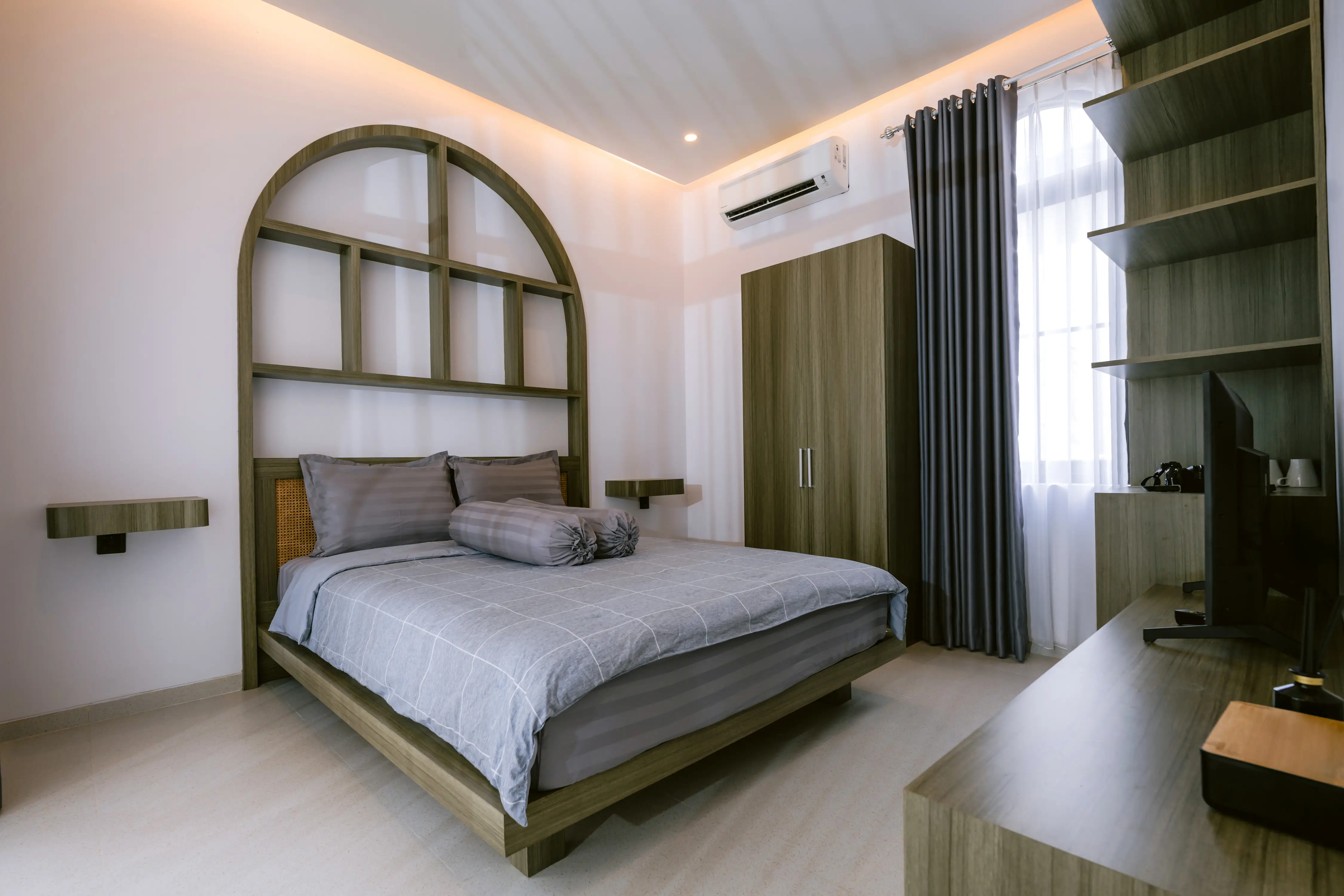 Bed facing TV with arched window beyond