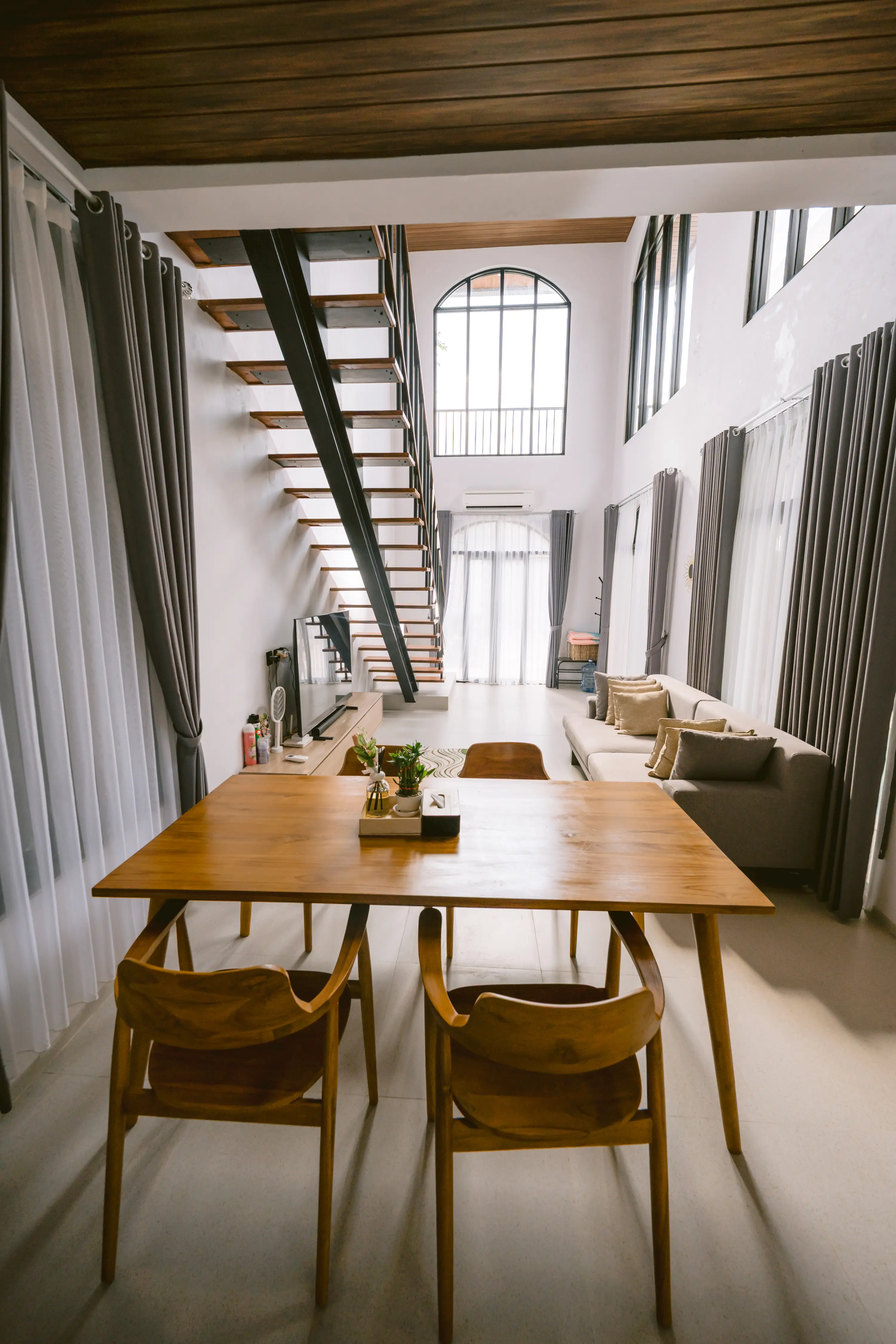 Wide view of living and dining areas with double-height ceiling